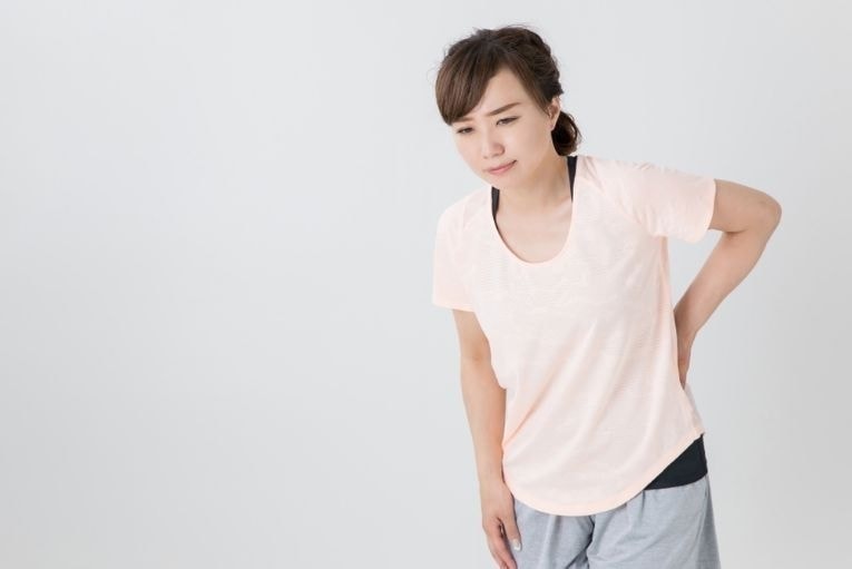 腰を抑えている女性画像